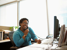 Businesswoman Sitting At Desk Using Telephone