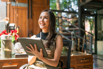 asian female adult creative designer happiness thinking work and reserach and make note of interesting ideas via tablet device,asian woman wokring casual relax at her home studio with window garden