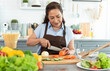 © NaMong Productions - Happy smiling asian older woman in apron cut vegetables while cooking salad in kitchen.