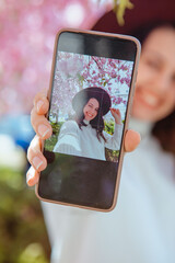 Canvas Print - woman shooting her self on the phone under blooming sakura tree