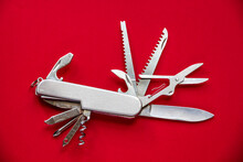 Metallic Swiss Knife Isolated On Red