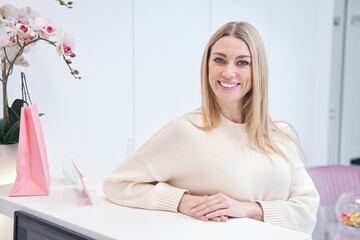 Joyful spa customer standing at reception desk and looking ahead