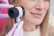 Dermatologist using dermoscopy device during patient skin check