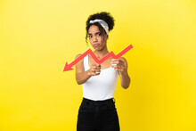 Young African American Woman Isolated On Yellow Background Holding A Downward Arrow And With Sad Expression