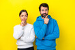 Young caucasian couple isolated on yellow background having doubts and with confuse face expression