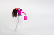 Young woman standing on tiptoe talking on phone and holding shopping bag on white background