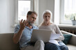 © fizkes - Elderly couple sit on sofa at home with laptop sorting out papers, reviewing expenses, feel angry due to utility bills going up. Financial crisis, bank debt notice, bankruptcy, lack of money concept