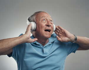 Wall Mural - This song has never sounded better. Shot of an elderly male wearing headphones and listening to music in a studio against a grey background.