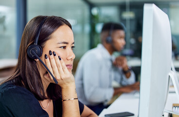 Canvas Print - When does this day end. Shot of a young call centre agent looking confused while using a desktop pc in an office.