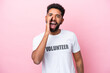 © luismolinero - Young volunteer man isolated on pink background shouting with mouth wide open
