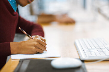 Aufkleber - Always make notes when studying. Shot of a unrecognizable student writing down notes while working on a computer in a library.