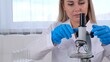 © Евгения Медведева - Female laboratory assistant analyzes samples using a microscope while working at a table in a laboratory, doing research