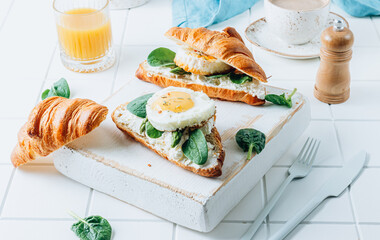 Wall Mural - Delicious Breakfast with Croissant sandwiches with Fried Egg, spinach, and Coffee and Orange Juice on white background,