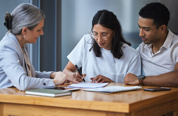 Signed yes on a promise to the future. Shot of a young couple meeting with a consultant to discuss paperwork an office.