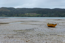 A Solo Yellow Rowing Boat On The Mud Flats At Low Tide With Beautiful Wild And Tranquil Landscape Of Raglan, New Zealand Aotearoa