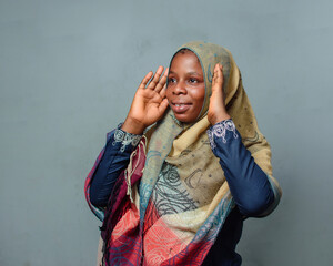 Wall Mural - An African Nigerian female muslim lady with Hijab scarf, engaging the process of prayer or ablution which is more noticeable during ramadan and when going to mosque