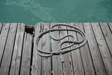 Old Wooden Boat Dock With Rope By Ocean Water