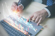 © Chaiwat - Financial, Investment, and Business concept. Businessman uses a laptop, pointing for analysis growth graph chart of corporate business. Plan strategy stock marketing for investment in the future.
