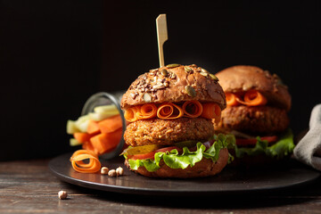 A combo of two vegan burgers and vegetable sticks with sauce. Low key, copy space.