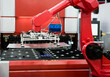 Robot arm loading metal sheet to laser cutting machine in production line. Industrial metalworking machinery.
