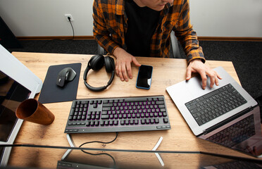 The guy in office working with the laptop and pc in the same time