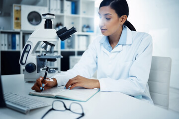 Wall Mural - she studied hard, she got far. shot of a young scientist writing notes while conducting medical rese