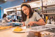 © unai - Female cafe owner cutting a snack for the customer to take with the latte