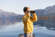 A boy with binoculars exploring the nature on the lake in the Austrian Alps