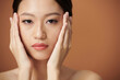 © DragonImages - Face of serious young Vietnamese woman touching her flawless soft skin and looking at camera