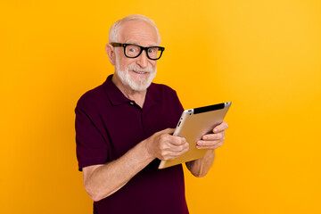 Photo of mature cheerful man chat type social media tablet app download isolated over yellow color background