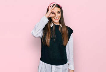 Wall Mural - Young beautiful woman wearing casual white shirt doing ok gesture with hand smiling, eye looking through fingers with happy face.