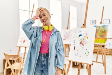 Canvas Print - Young caucasian girl at art studio smiling confident touching hair with hand up gesture, posing attractive and fashionable