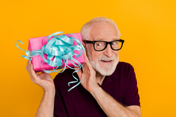 Sticker - Photo of cheerful mature man look curious get present box ribbon isolated over yellow color background