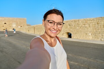 Wall Mural - Woman taking photo against the backdrop of historic fortress, sea bay