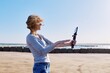 © Valerii Honcharuk - Middle-aged woman recording video on smartphone with outdoor on seashore