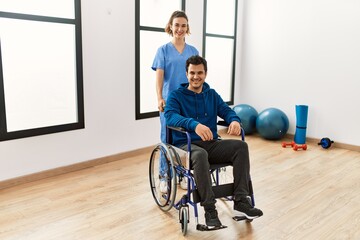 Wall Mural - Young physiotherapist woman and disabled man smiling happy at the clinic.