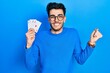 © Krakenimages.com - Young hispanic man playing poker holding cards screaming proud, celebrating victory and success very excited with raised arm
