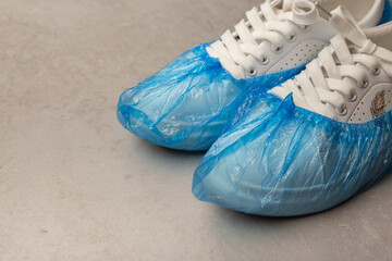 White sneakers in boot covers on a grey background. Minimalism