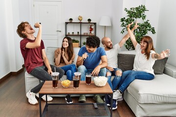 Wall Mural - Group of young friends having party singing song using microphone at home.