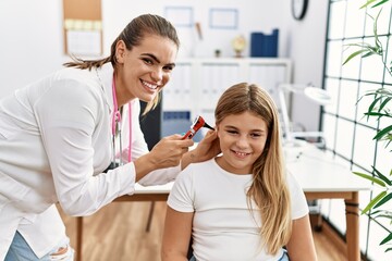 Canvas Print - Woman and girl doctor and patient examining ear using otoscope at clinic