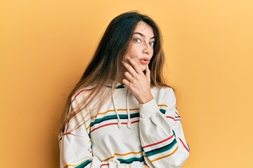 Poster - Young caucasian woman wearing casual clothes looking fascinated with disbelief, surprise and amazed expression with hands on chin