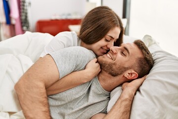 Canvas Print - Young caucasian couple smiling happy hugging on the bed at home.