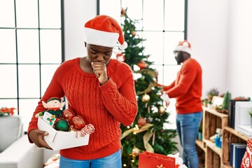 Wall Mural - Young african american couple standing by christmas tree feeling unwell and coughing as symptom for cold or bronchitis. health care concept.