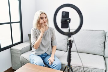 Poster - Young caucasian woman recording vlog tutorial with smartphone at home touching mouth with hand with painful expression because of toothache or dental illness on teeth. dentist