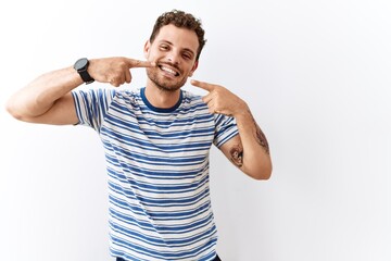 Sticker - Handsome young man standing over isolated background smiling cheerful showing and pointing with fingers teeth and mouth. dental health concept.