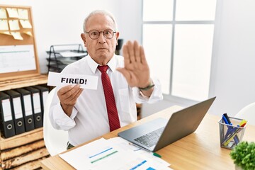 Wall Mural - Senior business man holding fired banner at the office with open hand doing stop sign with serious and confident expression, defense gesture