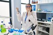 © Krakenimages.com - Young hispanic woman working at scientist laboratory covering mouth with hand, shocked and afraid for mistake. surprised expression