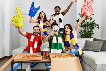 Wall Mural - Group of young friends watching and supporting soccer match at home.