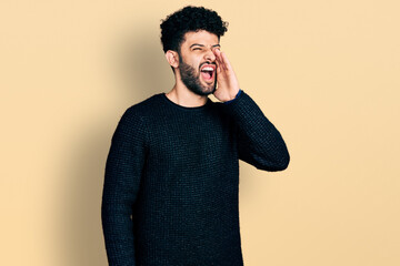 Poster - Young arab man with beard wearing casual winter sweater shouting and screaming loud to side with hand on mouth. communication concept.