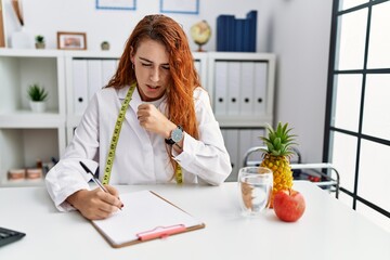 Poster - Young redhead woman nutritionist doctor at the clinic feeling unwell and coughing as symptom for cold or bronchitis. health care concept.